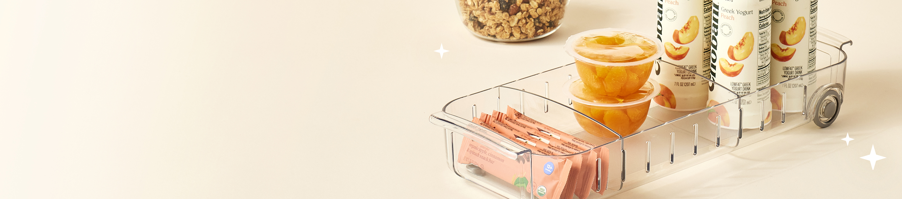 Clear plastic caddy organizer with snacks and drinks on a light background